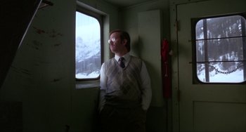 Movie still from “Never Cry Wolf” (1983), directed by Carroll Ballard – A man standing in front of a window looking outside; Medium shot, Low angle