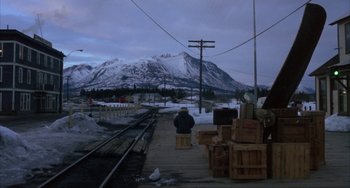 Movie still from “Never Cry Wolf” (1983), directed by Carroll Ballard – A person is sitting on a bench near a train track; Extreme Wide shot, High angle