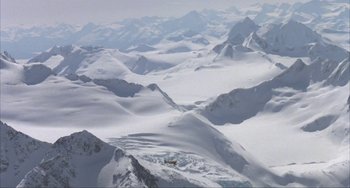 Movie still from “Never Cry Wolf” (1983), directed by Carroll Ballard – A view of a snowy mountain range from a helicopter; Extreme Wide shot, High angle