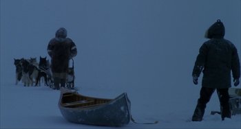 Movie still from “Never Cry Wolf” (1983), directed by Carroll Ballard – A man standing next to a boat in the snow; Extreme Wide shot, High angle