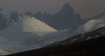 Movie still from “Never Cry Wolf” (1983), directed by Carroll Ballard – A mountain range with snow on the top of a hill; Extreme Wide shot, High angle