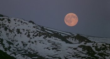 Movie still from “Never Cry Wolf” (1983), directed by Carroll Ballard – A full moon setting over a snow covered mountain; Extreme Wide shot, Low angle