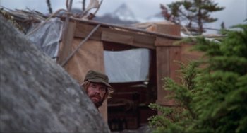 Movie still from “Never Cry Wolf” (1983), directed by Carroll Ballard – A man with a beard wearing a hat and looking at the camera; Medium shot, Low angle