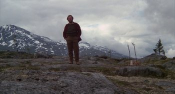 Movie still from “Never Cry Wolf” (1983), directed by Carroll Ballard – A man standing on top of a mountain with snow covered mountains in the background; Wide shot, Low angle