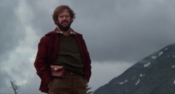 Movie still from “Never Cry Wolf” (1983), directed by Carroll Ballard – A man standing in front of a mountain with his hands in his pockets; Medium shot, Low angle