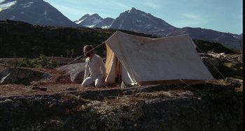 Movie still from “Never Cry Wolf” (1983), directed by Carroll Ballard – A man sitting in front of a tent in the mountains; Wide shot, High angle