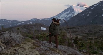 Movie still from “Never Cry Wolf” (1983), directed by Carroll Ballard – A man standing on top of a mountain holding a camera; Wide shot, Low angle