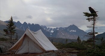 Movie still from “Never Cry Wolf” (1983), directed by Carroll Ballard – A tent pitched in the middle of a field with mountains in the background; Extreme Wide shot, High angle
