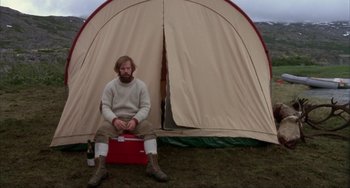 Movie still from “Never Cry Wolf” (1983), directed by Carroll Ballard – A man sitting in front of a tent in a field; Wide shot, Low angle