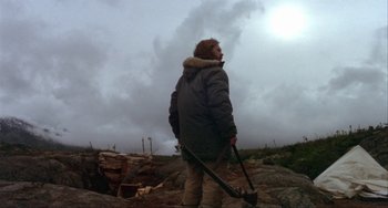 Movie still from “Never Cry Wolf” (1983), directed by Carroll Ballard – A man standing on top of a hill holding a shovel; Wide shot, Low angle