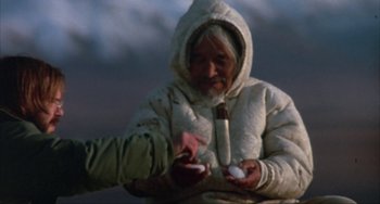 Movie still from “Never Cry Wolf” (1983), directed by Carroll Ballard – An old man wearing a white jacket holding a white object; Medium shot, High angle