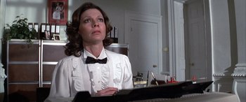 Movie still from “Never Say Never Again” (1983), directed by Irvin Kershner – A woman wearing a white shirt and a bow tie; Medium shot, Low angle