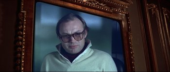 Movie still from “Never Say Never Again” (1983), directed by Irvin Kershner – A man wearing glasses and a sweater is looking at himself in the mirror; Close Up shot, Low angle