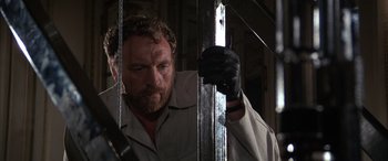 Movie still from “Never Say Never Again” (1983), directed by Irvin Kershner – A man with a beard is holding on to a metal bar; Close Up shot, Low angle