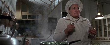 Movie still from “Never Say Never Again” (1983), directed by Irvin Kershner – A woman wearing a chef's hat holding a cup; Close Up shot, Over the shoulder angle