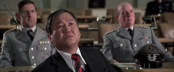 Movie still from “Never Say Never Again” (1983), directed by Irvin Kershner – A man wearing a suit and tie sitting in front of another man; Close Up shot, Low angle