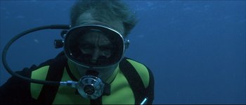 Movie still from “Never Say Never Again” (1983), directed by Irvin Kershner – A man in a yellow and black wetsuit is underwater; Medium shot, Low angle
