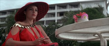 Movie still from “Never Say Never Again” (1983), directed by Irvin Kershner – A woman wearing a red hat and holding a cigarette in her hand; Close Up shot, Low angle