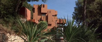 Movie still from “Never Say Never Again” (1983), directed by Irvin Kershner – A building that has been painted orange and has a plant growing on it's side; Extreme Wide shot, Low angle