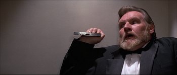 Movie still from “Never Say Never Again” (1983), directed by Irvin Kershner – A man in a suit holding a cell phone in his hand; Close Up shot, Low angle
