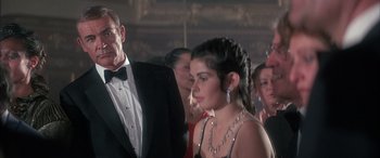 Movie still from “Never Say Never Again” (1983), directed by Irvin Kershner – A group of people standing in a room; Close Up shot, Over the shoulder angle