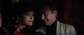 Movie still from “Never Say Never Again” (1983), directed by Irvin Kershner – A man and a woman smiling for the camera; Close Up shot, Over the shoulder angle