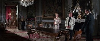 Movie still from “Never Say Never Again” (1983), directed by Irvin Kershner – A man and a woman standing in front of a table; Wide shot, High angle