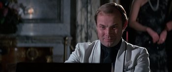 Movie still from “Never Say Never Again” (1983), directed by Irvin Kershner – A person sitting at a table; Close Up shot, Low angle