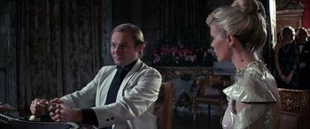 Movie still from “Never Say Never Again” (1983), directed by Irvin Kershner – A man sitting in a chair in front of a woman; Medium shot, Over the shoulder angle