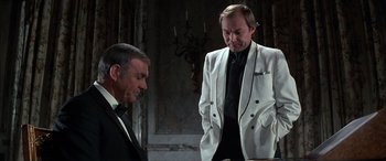 Movie still from “Never Say Never Again” (1983), directed by Irvin Kershner – A man in a white jacket and a man in a black tie; Medium shot, Over the shoulder angle