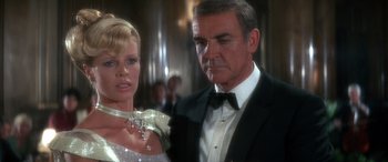 Movie still from “Never Say Never Again” (1983), directed by Irvin Kershner – A man and a woman in formal wear standing next to each other; Close Up shot, Low angle