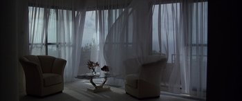 Movie still from “Never Say Never Again” (1983), directed by Irvin Kershner – A living room with a glass coffee table and a vase of flowers on the table; Extreme Wide shot, Low angle