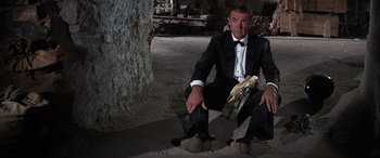 Movie still from “Never Say Never Again” (1983), directed by Irvin Kershner – A man in a tuxedo sitting on the ground; Wide shot, Low angle