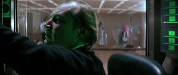 Movie still from “Never Say Never Again” (1983), directed by Irvin Kershner – A man sitting in a chair in front of a wall; Close Up shot, Over the shoulder angle