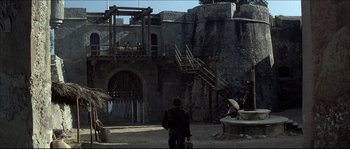 Movie still from “Never Say Never Again” (1983), directed by Irvin Kershner – A man standing in front of an old building; Extreme Wide shot, High angle
