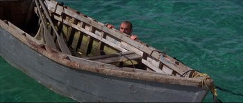 Movie still from “Never Say Never Again” (1983), directed by Irvin Kershner – A man in a wooden boat in the water; Wide shot, High angle