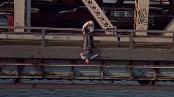 Movie still from “New Jack City” (1991), directed by Mario Van Peebles – A man hanging upside down on a bridge; Wide shot, Overhead angle
