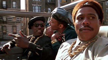 Movie still from “New Jack City” (1991), directed by Mario Van Peebles – A group of men sitting next to each other on top of a building; Medium shot, Low angle
