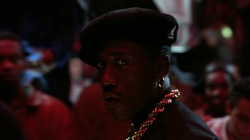 Movie still from “New Jack City” (1991), directed by Mario Van Peebles – A person wearing a hat and a necklace; Close Up shot, Low angle