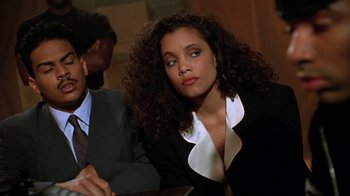 Movie still from “New Jack City” (1991), directed by Mario Van Peebles – A woman sitting at a table; Close Up shot, Low angle