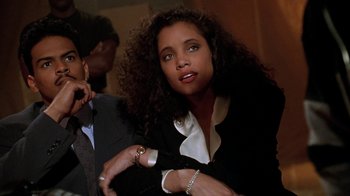 Movie still from “New Jack City” (1991), directed by Mario Van Peebles – A young woman with curly black hair sitting next to a man; Close Up shot, Low angle