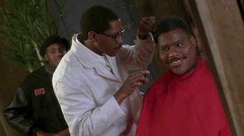Movie still from “New Jack City” (1991), directed by Mario Van Peebles – A man getting his hair cut by another man; Medium shot, Low angle