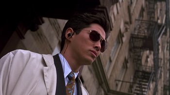 Movie still from “New Jack City” (1991), directed by Mario Van Peebles – A man in a suit and sunglasses is listening to music; Close Up shot, Low angle