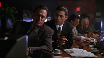 Movie still from “New Jack City” (1991), directed by Mario Van Peebles – A group of men sitting around a table; Medium shot, Low angle