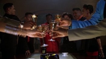 Movie still from “New Jack City” (1991), directed by Mario Van Peebles – A group of people toasting with wine glasses at a party; Medium shot, Low angle