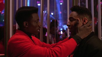 Two young men in red jackets touching each other's hair