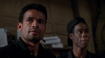 Movie still from “New Jack City” (1991), directed by Mario Van Peebles – Two men standing next to each other in front of a wall; Close Up shot, Low angle