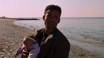 Movie still from “New Jack City” (1991), directed by Mario Van Peebles – A man holding a baby on the beach; Close Up shot, Low angle