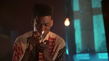 Movie still from “New Jack City” (1991), directed by Mario Van Peebles – A man lighting a cigarette in a room with lights; Close Up shot, Low angle