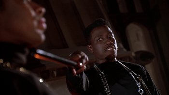 Movie still from “New Jack City” (1991), directed by Mario Van Peebles – A man holding a stick in a room; Close Up shot, Low angle